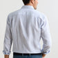 A man is shown from the back wearing the Peter Millar Astino Lino Stripe Sport Shirt in light blue and white Italian linen with mother-of-pearl buttons, paired with blue jeans, against a plain background.