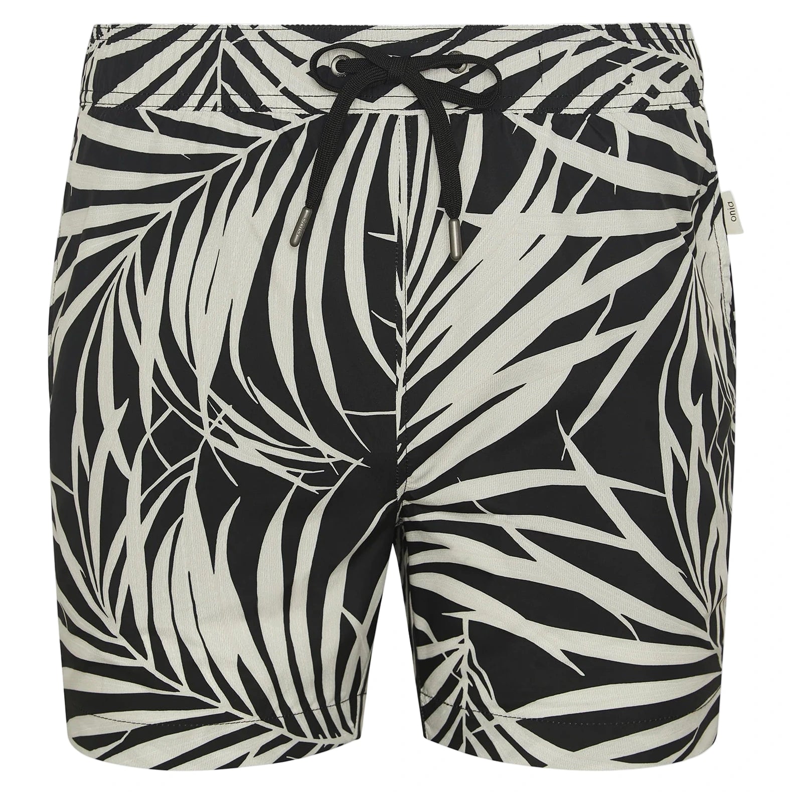 The Charles 5" Swim Trunk by Onia features a black design with a white palm leaf pattern, classic tailoring, a black drawstring waist, and a small fabric tag on the side.