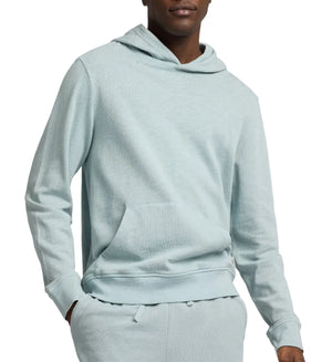 A person wearing an Onia Terry Pullover Hoodie in light blue heavyweight cotton with matching sweatpants, hands in the front pocket.