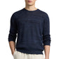 A person wears the Onia Silk Linen Crewneck, a navy blue long-sleeve sweater, with light pants and stands hands-in-pockets against a white background.