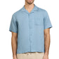 A man wearing the Onia Air Linen Convertible Vacation Shirt in light blue with short sleeves and a chest pocket, paired with beige pants, stands against a white background.