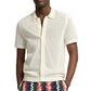 A person wearing the Onia Crochet Knit Button Up, a short-sleeve off-white cotton shirt with a collar, paired with colorful zigzag patterned pants—ideal for warm-weather layering.