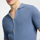 A person wearing the Onia Drop Needle Button Up—a light blue, short-sleeve cotton shirt with textured fabric and two visible buttons—shown from shoulders to mid-torso.