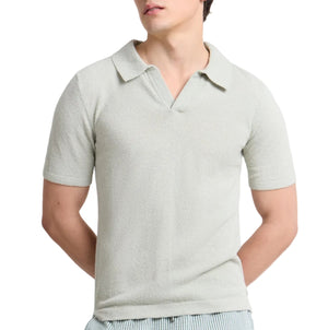 A person wears the Onia Boucle Knit Johnny Polo in light gray, featuring a V-neck, textured boucle yarn fabric, and a relaxed silhouette, while standing with arms behind their back.