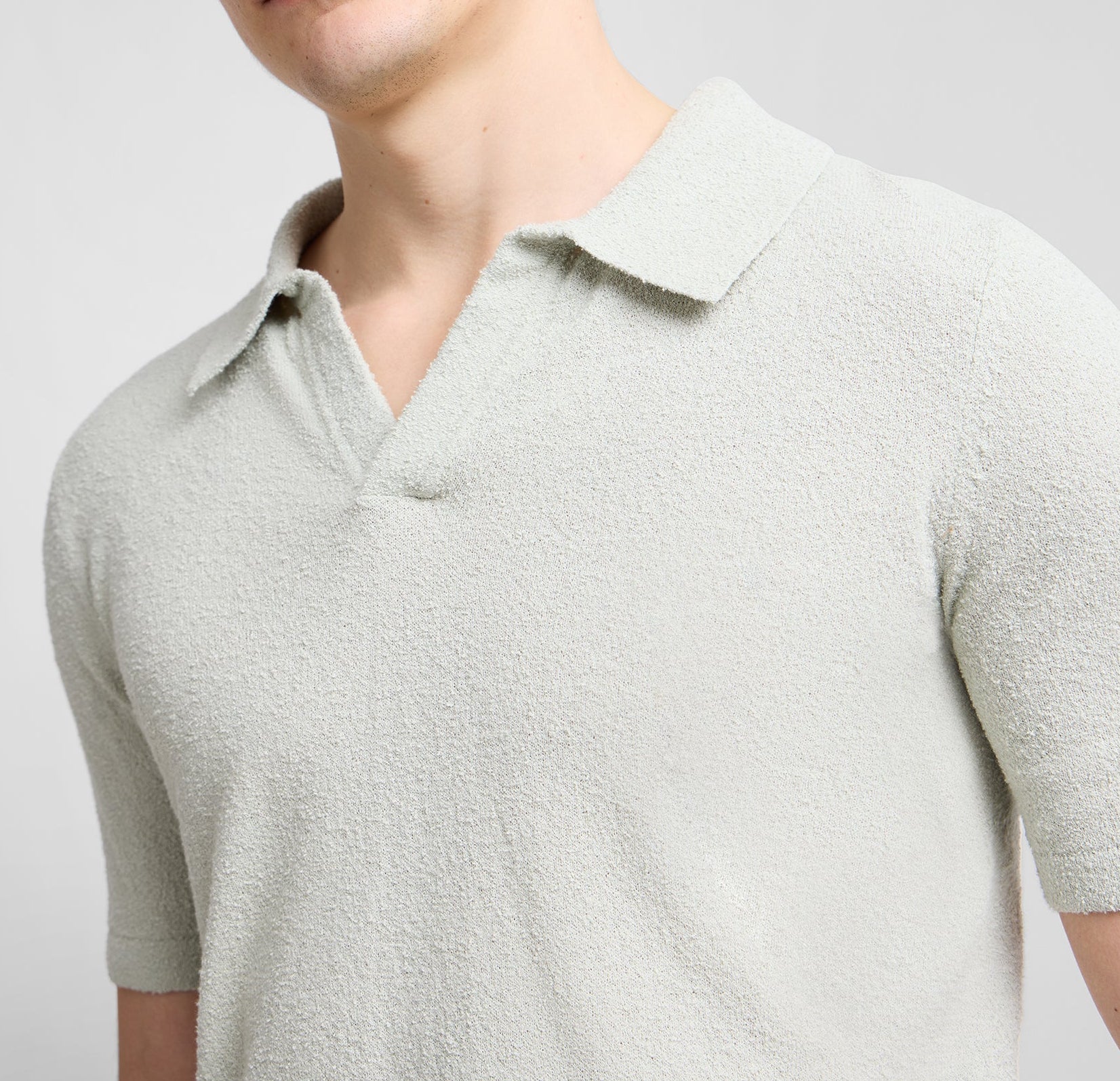 A person wears the Onia Boucle Knit Johnny Polo in light grey with short sleeves and a textured boucle knit, shown from shoulders to mid-torso.