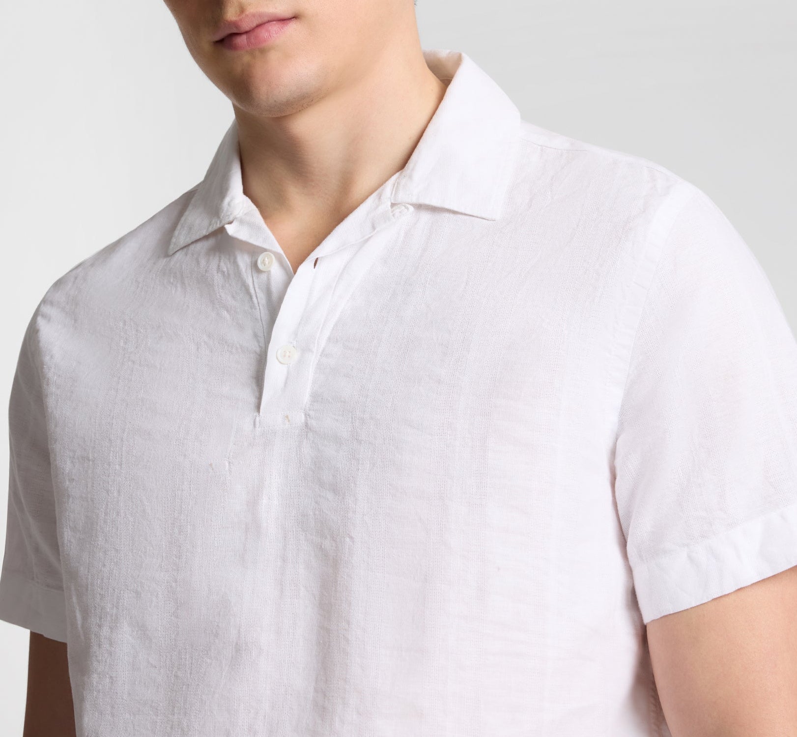 A person wearing the Onia Cotton Linen Pop-Over Polo, shown from shoulders to mid-torso, showcases its breathable comfort and relaxed silhouette.