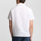 A person is shown from the back wearing the Onia Cotton Linen Pop-Over Polo, a white short-sleeve shirt designed for breathable comfort, paired with blue striped pants against a plain background.