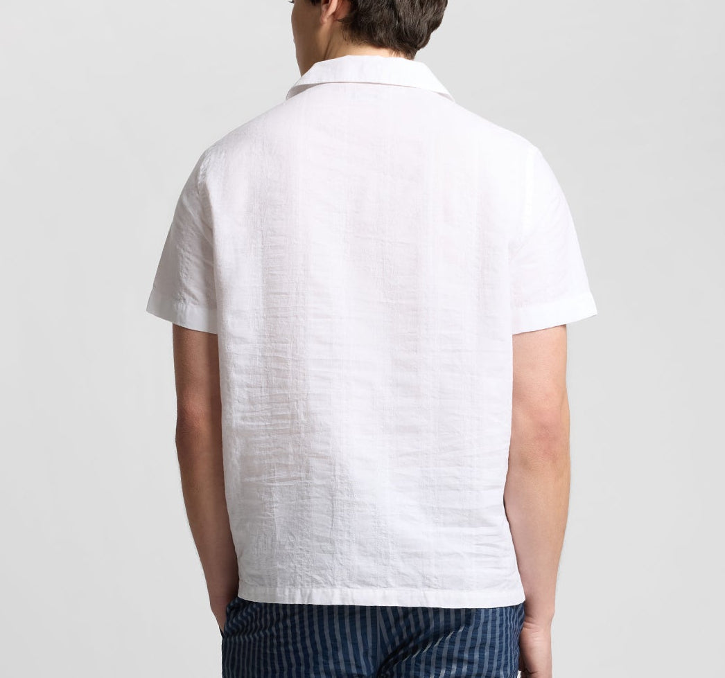 A person is shown from the back wearing the Onia Cotton Linen Pop-Over Polo, a white short-sleeve shirt designed for breathable comfort, paired with blue striped pants against a plain background.
