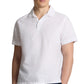 A man wears the Onia Cotton Linen Pop-Over Polo, a short-sleeve white top with a button placket, offering breathable comfort and a relaxed, casual silhouette against a plain background.
