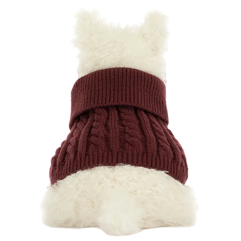 A white fluffy dog sits with its back to the camera, wearing a cozy maroon Munro Scottie Dog Winter Jumper Outfit by Jellycat with a wide turtleneck.