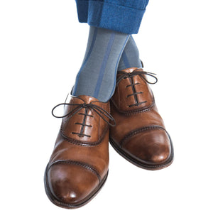 A person in blue trousers and Dapper Classics Steel Gray with Indigo Blue Vertical Stripe Cotton Sock Linked Toe Mid Calf socks, paired with brown leather dress shoes, stands on a white background.