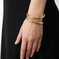 A close-up of a hand wearing three Lie Studio Maggie Bracelets highlights their versatile style, beautifully paired with a black dress.