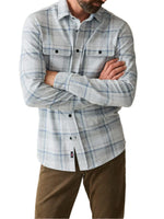 Man standing with arms crossed, wearing the popular Faherty Legend™ Sweater Shirt and brown pants on a white background, highlighting its versatile flannel style.