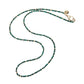 The Jane Win Double Wrap Beaded Necklace is a versatile piece adorned with small green and gold beads, featuring a gold clasp and a circular charm, displayed on a white background.