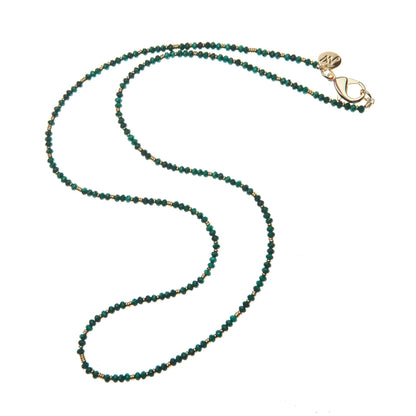 The Jane Win Double Wrap Beaded Necklace is a versatile piece adorned with small green and gold beads, featuring a gold clasp and a circular charm, displayed on a white background.
