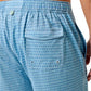 Close-up of a person wearing light blue Johnnie-O Malta Swim Trunks, displaying fun prints on the back and side. The design includes a flap pocket and an elastic waistband for comfort.