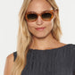 Wearing Krewe's Margaret Sunglasses, a woman with long blonde hair and a sleeveless dark top stands against a white background, exuding bold, modern style.