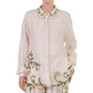A person wearing the cream floral Cecilia Shirt with embroidered collar and hem by Agua By Agua Bendita, paired with striped pants.