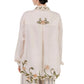 A person, facing away from the camera, wears the Cecilia Shirt by Agua By Agua Bendita with floral embroidery on the back, collar, and hem, paired with matching striped trousers.