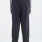 Viewed from behind, person wears Maria McManus Barrel Leg Drawstring Trouser in black Japanese cotton with back pockets, a grey ribbed long-sleeve top, and heeled sandals.