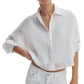 A person wears the Rag & Bone Marin Combo Shirt—a loose, white, long-sleeve embroidered cotton top with subtle stripes—paired with white pants for a relaxed silhouette.