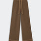 The Marquise Pant by Guest in Residence features a relaxed straight leg silhouette and a matching fabric belt, designed in brown with a repeating geometric diamond pattern, shown laid flat on a light background.