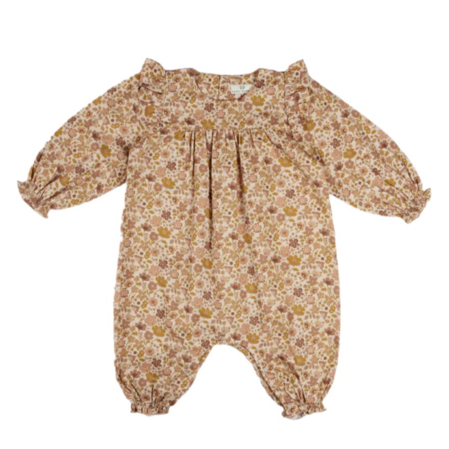 The Early Sunday Baby Martha Overalls Romper features long sleeves and ruffled cuffs, showcasing a garden floral print of small pink and brown flowers on a beige background.