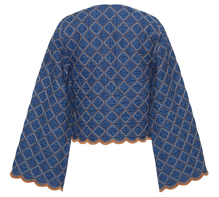 The Cara Cara Marvis Jacket is a blue quilted denim piece with a diamond pattern, wide sleeves, contrasting stitching, and a scallop edge hem, shown from the back.