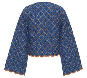 The Cara Cara Marvis Jacket is a blue quilted denim piece with a diamond pattern, wide sleeves, contrasting stitching, and a scallop edge hem, shown from the back.