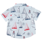 The Boys' Jack Shirt by Pink Chicken is a short-sleeve white shirt with a navy and red nautical print—sailboats, lighthouses, anchors, compasses, and seagulls—ideal for kids who love water adventures.