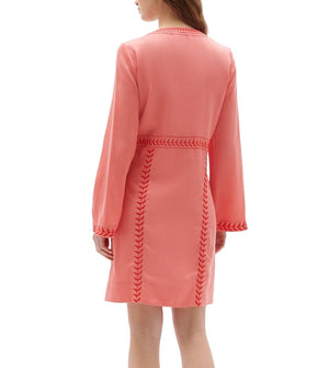 A person wearing a Figue Melissa Dress, viewed from behind, which features long sleeves with braided and embroidery detailing along the sleeves and waist.