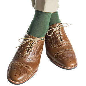 Person wearing Forest Green Ribbed Cotton Sock Linked Toe Mid-Calf by Dapper Classics, beige pants, and brown leather brogues on a white background. These men's socks are crafted in North Carolina for a refined touch.