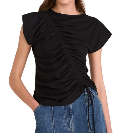 Woman wearing a black adjustable Merlette New York Reverie Jersey Top with a drawstring on one side, paired with blue jeans.