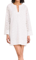 Woman in a Merlette New York white cotton eyelet dress with a v-neckline and perforated bell sleeves.