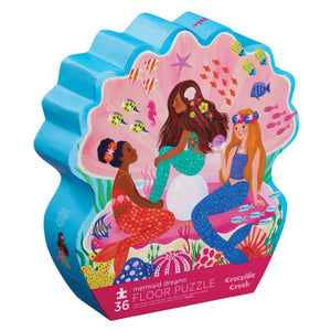 The image showcases the vibrant, shell-shaped box of the Crocodile Creek Mermaid Dreams 36 Piece Puzzle. This delightful puzzle features an underwater fantasy scene with three mermaids amidst sea creatures and corals.