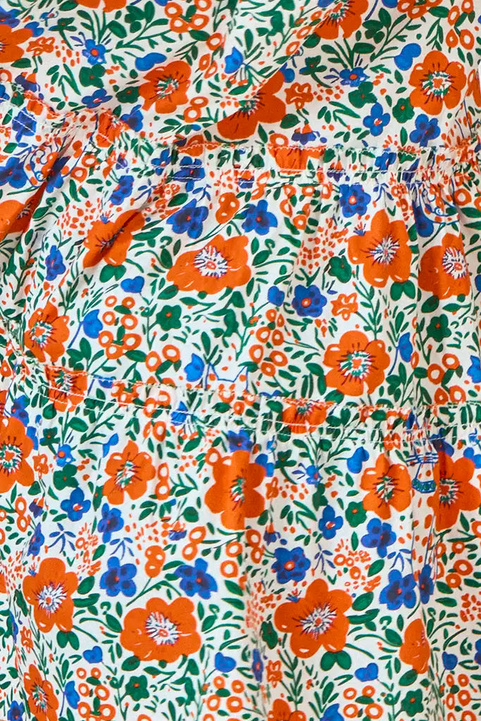 Close-up of the Girls' Merritt Dress by Hunter Bell NYC: floral fabric with red-orange, blue, and green flowers and leaves on white, inspired by the original design and finished with a charming ruffled neckline.
