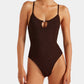 A woman wearing the Hunza G Mia Beaded Swim one-piece in dark brown, featuring thin straps and a small front keyhole cutout.