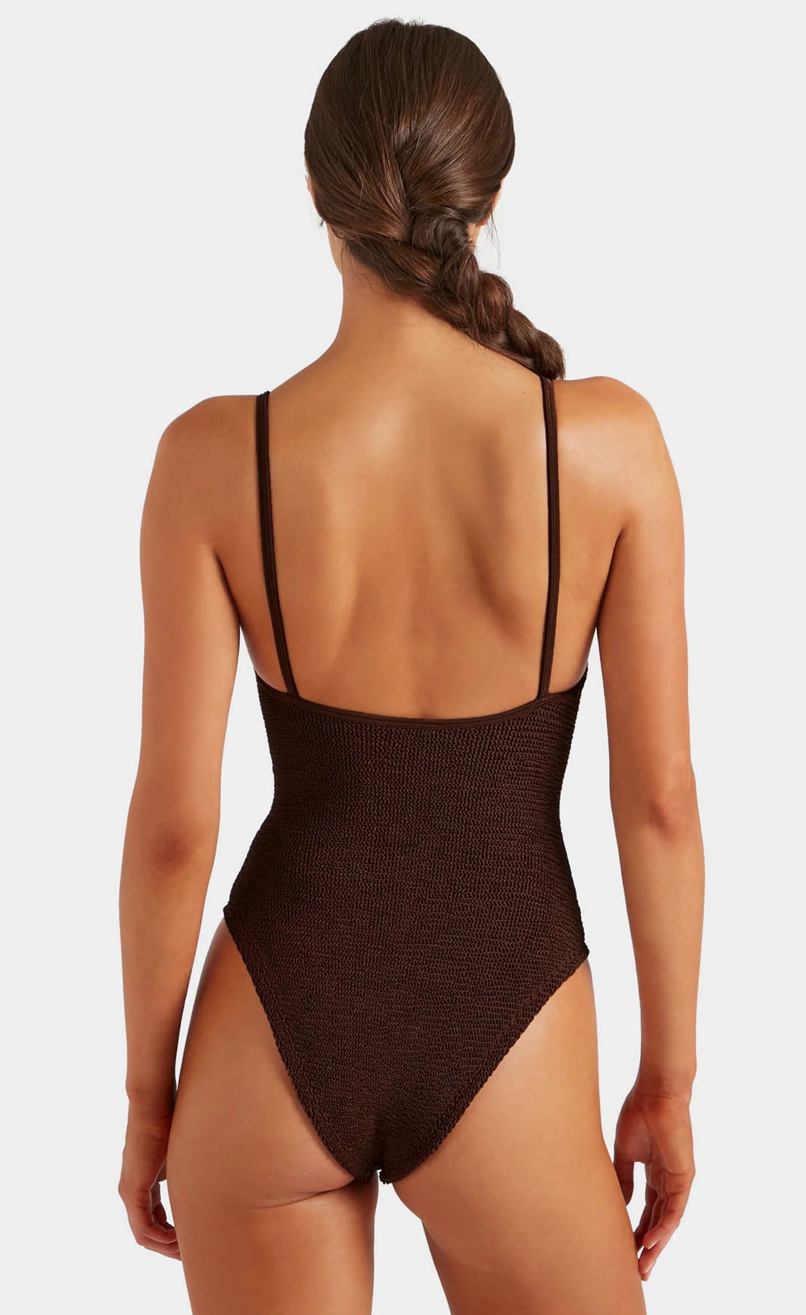 Woman with braided hair wearing a dark brown Hunza G Mia Beaded Swim one-piece, shown from the back against a plain background.