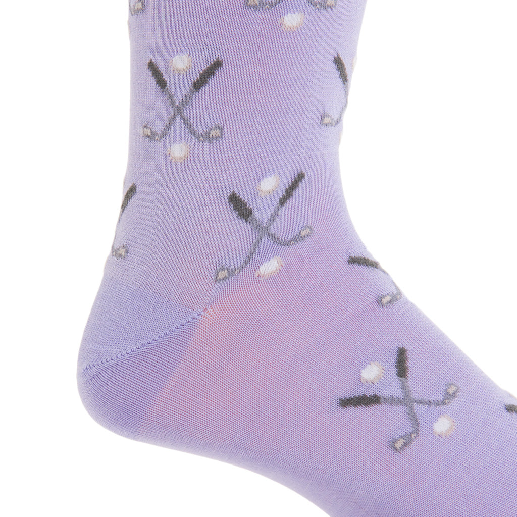 Close-up of a sock by Dapper Classics, made in the USA, showcasing a pattern of crossed golf clubs and golf balls in steel gray and white.