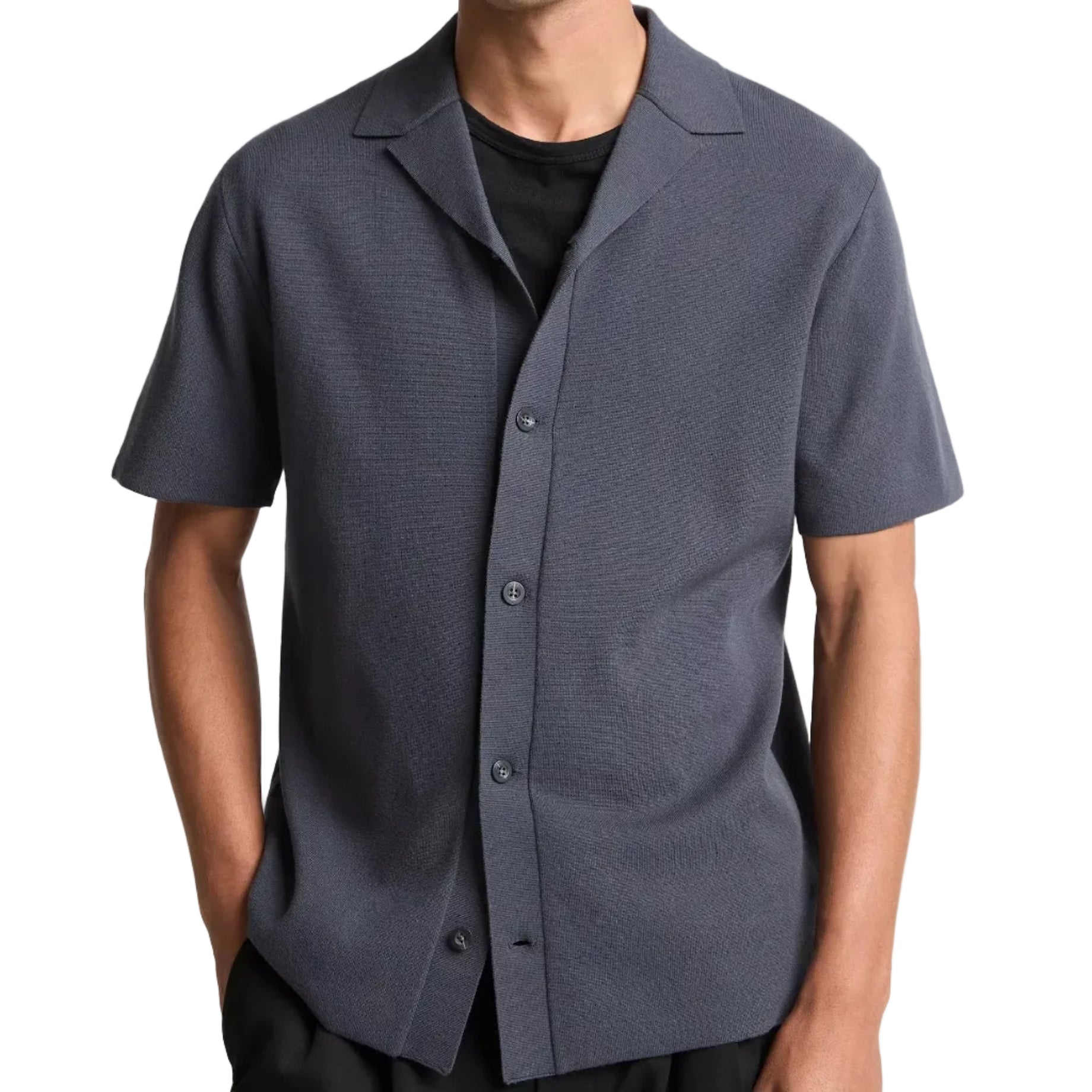 A person wears the vince Milano Shortsleeve Cabana in dark gray over a black t-shirt, standing with hands in pockets against a white background.