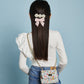 Woman from behind showcasing a floral hair accessory made from Milledeux Small Chain Bag, Liberty Print fabric and a decorative quilted flap bag with metal closure.