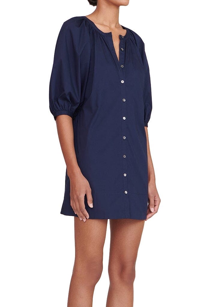 The model is wearing a Staud Mini Vincent Dress with navy button down dress with balloon sleeves.