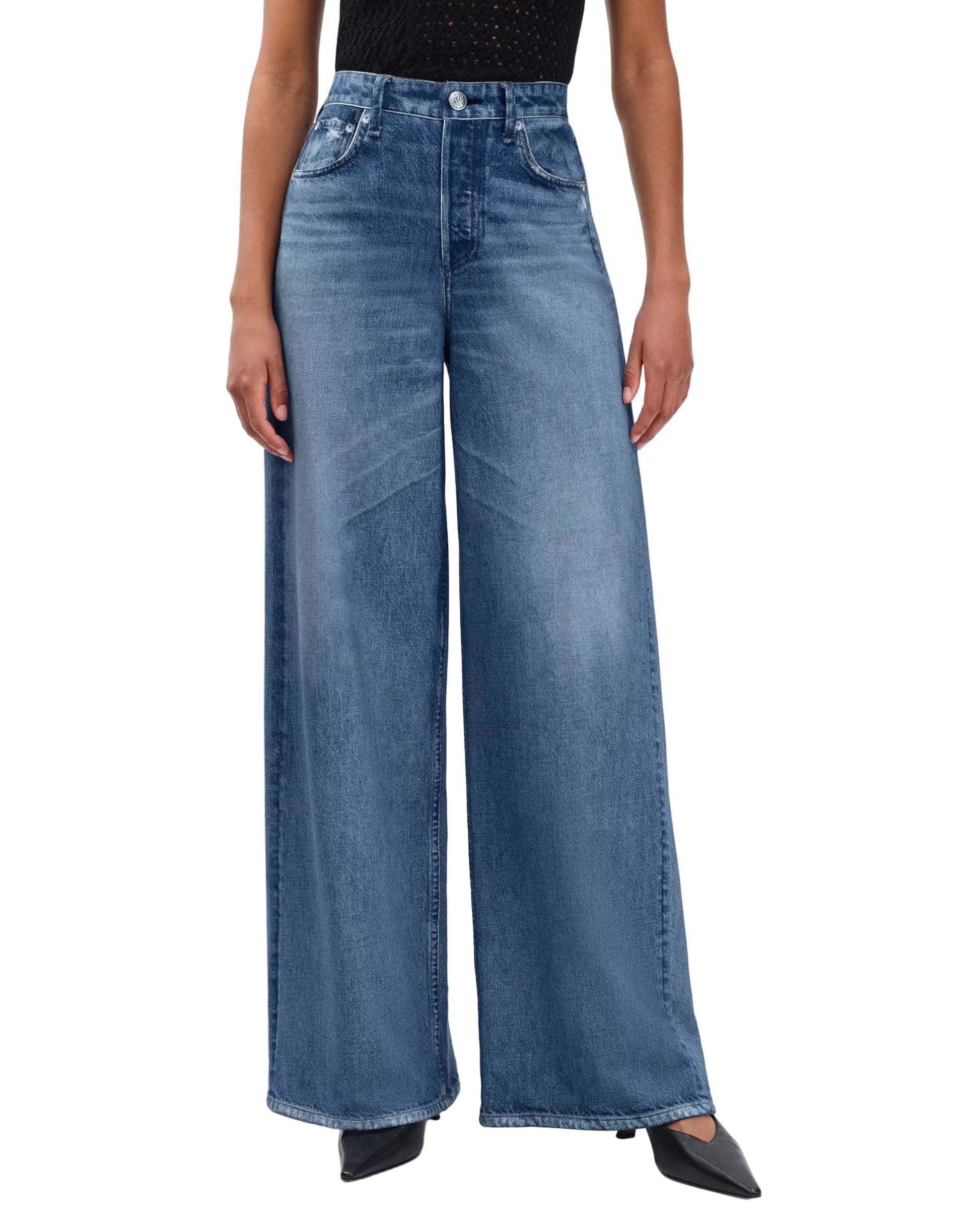 Person wearing Rag & Bone Miramar Sofie Ankle high-waisted, wide-leg blue jeans with a black sleeveless top, standing with arms relaxed and facing forward.