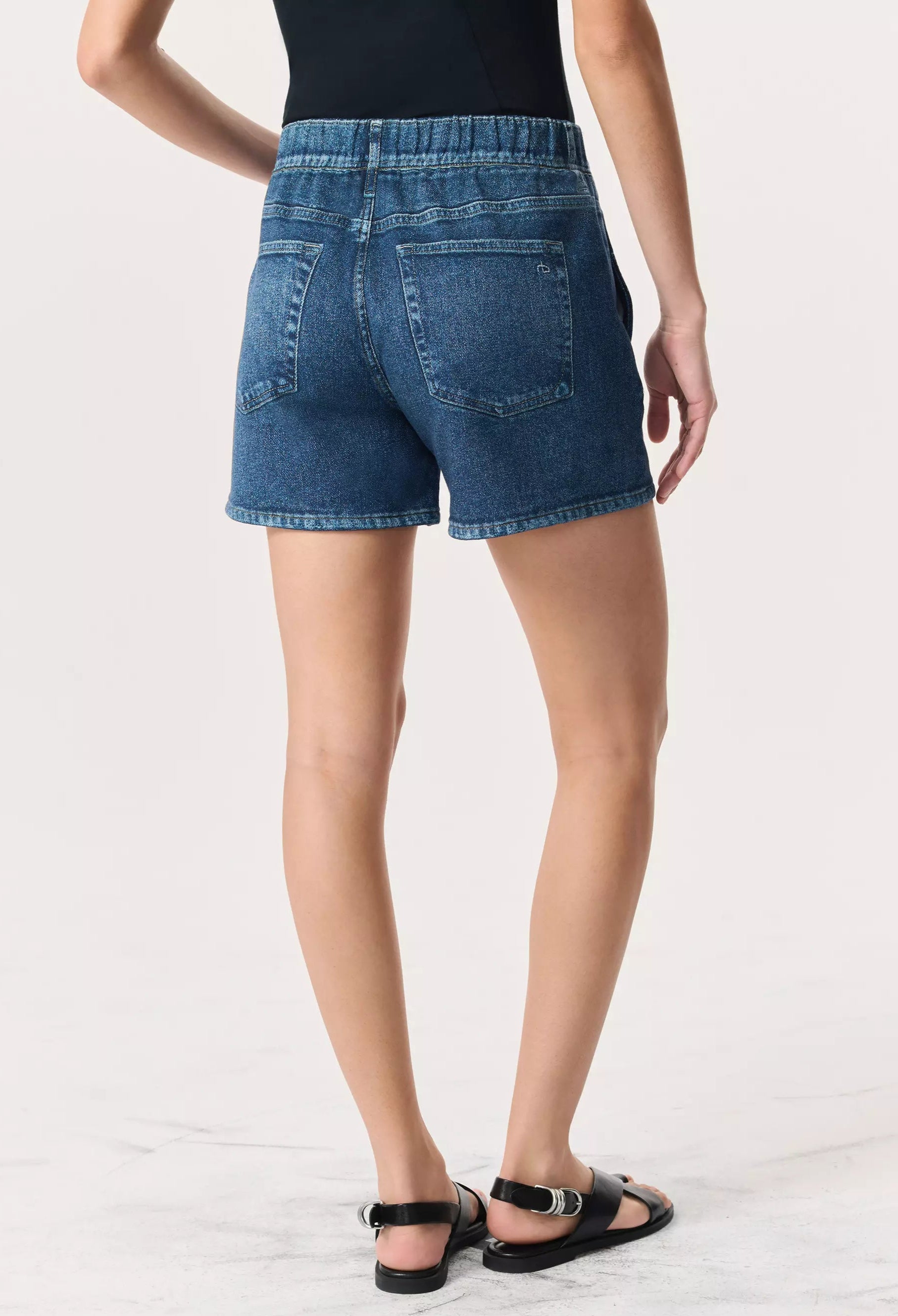 Person wearing Rag & Bone's Miramar Terry Walking Short with a pull-on elastic waistband, styled with a black top and sandals, stands with their back to the camera against a plain light background.