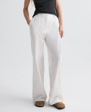 A person wearing a black sleeveless top, brown shoes, and TWP's Hudson St. Cotton Stripes Pant stands against a plain light background.