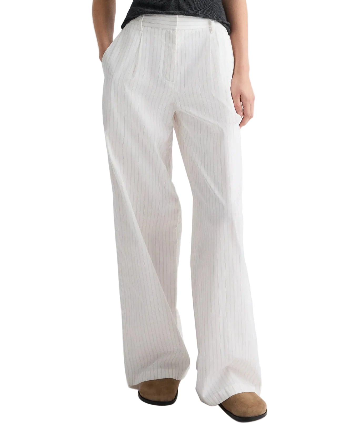 A person demonstrates a chic wide-leg silhouette in the TWP Hudson St. Cotton Stripes Pant, featuring subtle vertical stripes, paired with a dark top and brown shoes.