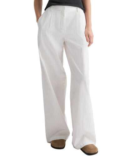 A person demonstrates a chic wide-leg silhouette in the TWP Hudson St. Cotton Stripes Pant, featuring subtle vertical stripes, paired with a dark top and brown shoes.