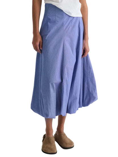 Person wearing a white shirt, TWP Full Intentions Cotton Poplin Skirt in light blue micro check, and brown suede shoes, standing against a white background.