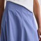 A person wearing a white shirt tucked into the TWP Full Intentions Cotton Poplin Skirt, a high-waisted, light blue A-line style.