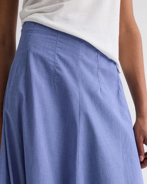 A person wearing a white shirt tucked into the TWP Full Intentions Cotton Poplin Skirt, a high-waisted, light blue A-line style.